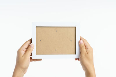 Low section of person holding paper against white background