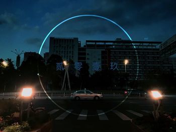 Cars on road by illuminated buildings against sky at night