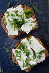 Avocadocreme unter schafskäse bestreut mit weizengras auf vollkornbrot