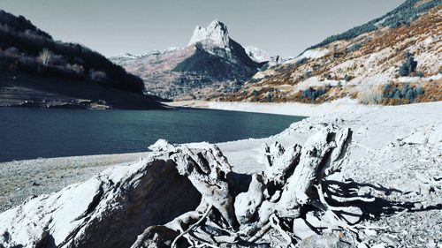Scenic view of frozen lake by snowcapped mountains against sky