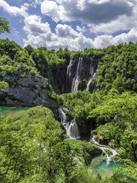 Scenic view of waterfall in forest against sky