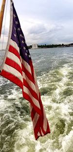 Close-up of flag on sea against sky