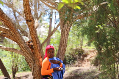 Portrait of boy with tree trunk against plants