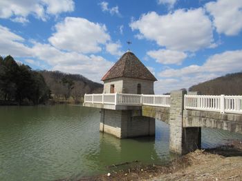 Bridge over lake by building against sky