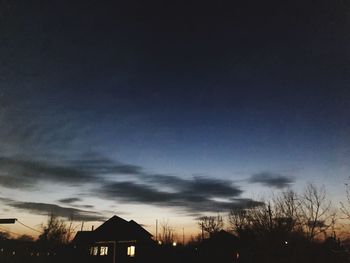 Silhouette buildings and trees against sky at dusk