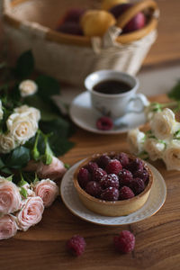 Raspberries dessert with coffee and flowers on table