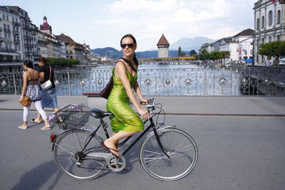 Full length of young woman riding bicycle in city