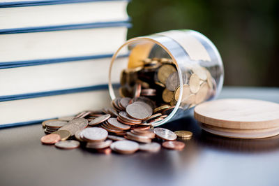 Stack of books by spilling coins on table