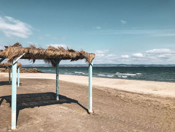 Deck chairs on beach against sky