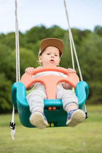 Portrait of boy swinging at playground