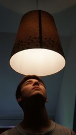 Close-up of man looking at illuminated lighting equipment at home