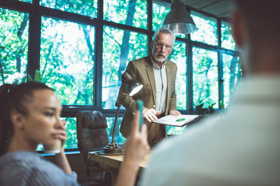 Side view of businesswoman using mobile phone while standing in office