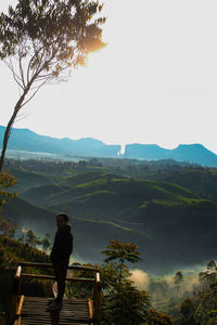Rear view of man looking at mountains against sky