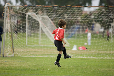 Young boy skipping in front of goal on a soccer field