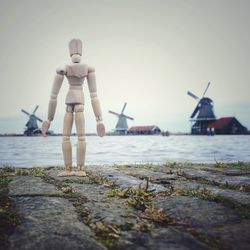 Wooden figurine at lakeshore against sky