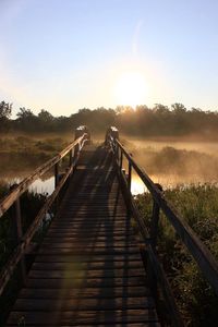 Jetty leading towards lake against clear sky