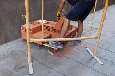 Construction work - mason lifting a heavy red brick with gloves.