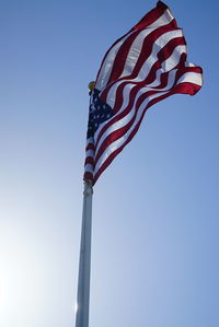 Low angle view of flags against clear blue sky