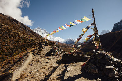 Colorful prayer flags hanging on mountain against blue sky during sunny day