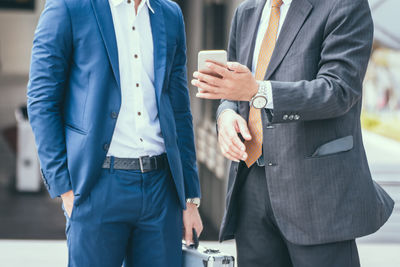 Midsection of businessmen with mobile phone