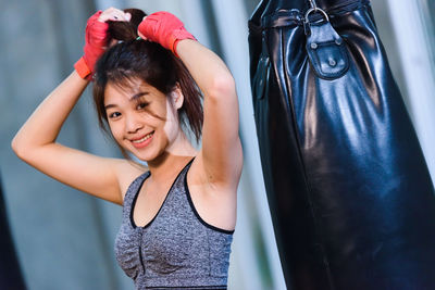 Portrait of female boxer standing against wall