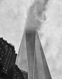 Low angle view of skyscrapers against cloudy sky