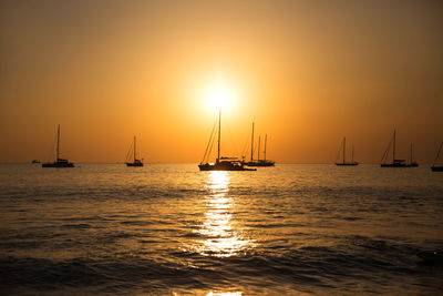 Sailboat sailing on sea against sky during sunset