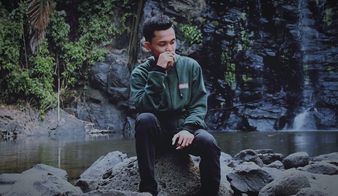 real people, one person, rock, young adult, sitting, solid, water, rock - object, forest, young men, lifestyles, leisure activity, nature, full length, front view, casual clothing, tree, outdoors, contemplation, flowing water