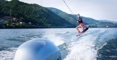 Full length of young woman wakeboarding on sea