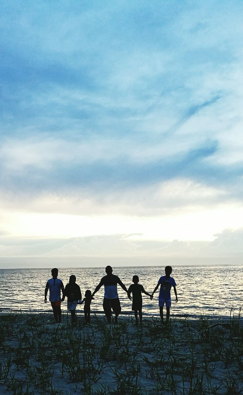 FRIENDS ON BEACH AGAINST SKY