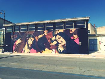 Graffiti on wall by street against clear sky