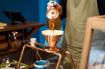 Midsection of chef filtering coffee in glass on table