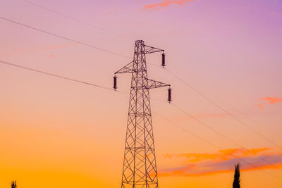 Low angle view of electricity pylon against sky during sunset