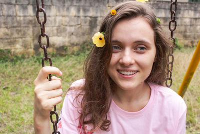 Portrait of young woman swinging at playground
