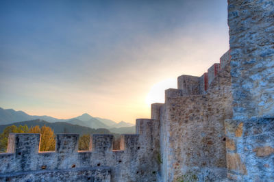 Low angle view of surrounding wall against sky during sunset