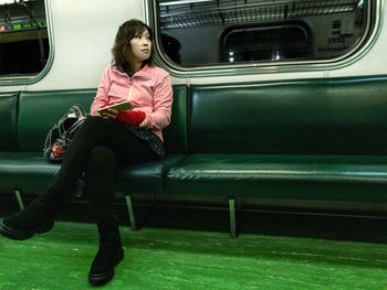 Full length of woman sitting in train