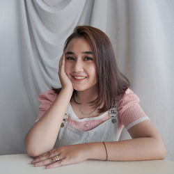 Portrait of young woman sitting on bed at home