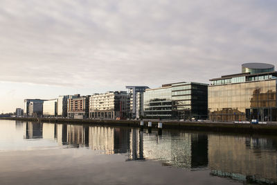 Buildings in dublin by river liffey  against sky in city