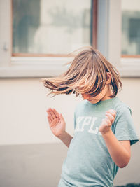 Cute girl playing while standing against wall