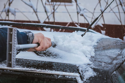 Young teen cleaning snow from the back of the car