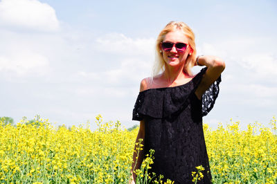 Portrait of smiling young woman standing on oilseed rape field