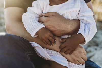 Close up detail of father embracing young child with arms wrapped