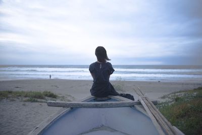 Woman sitting on boat on beach