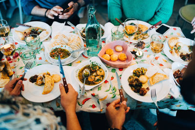 Midsection of young multi-ethnic friends eating lunch at restaurant during party