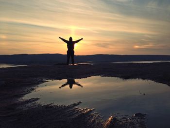 Silhouette of woman jumping on beach