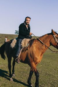 Man riding horse on field against sky