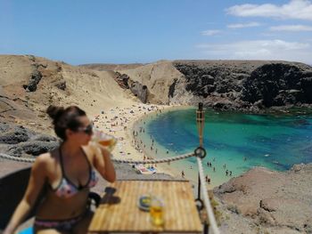 Rear view of woman photographing on beach