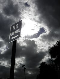 Low angle view of road sign against cloudy sky