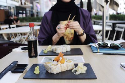 Midsection of woman having sushi at restaurant