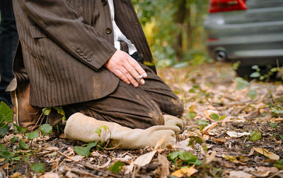 Low section of man in suit standing on autumn leaves